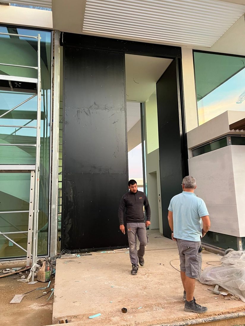 Detalle de puerta pivotante con instalación y ajuste de precisión